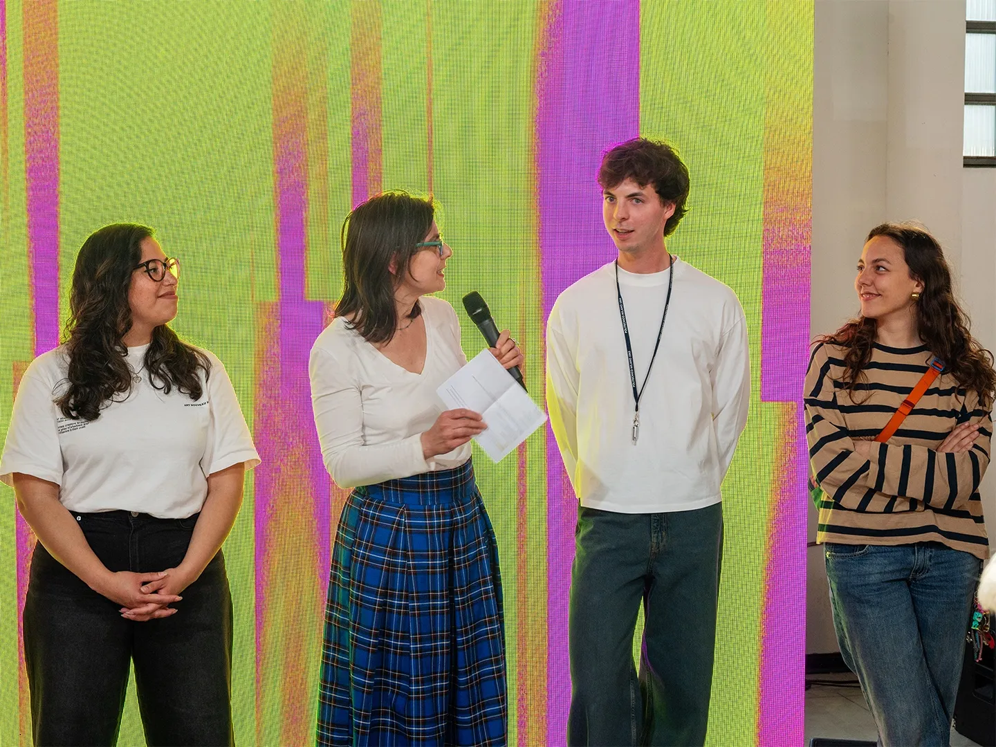 Four people speaking on stage in front of a yellow and magenta backdrop