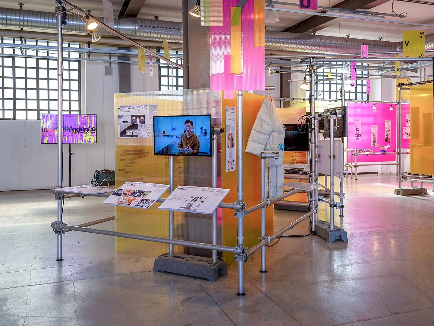 Exhibition stands with yellow and magenta panels and a screen