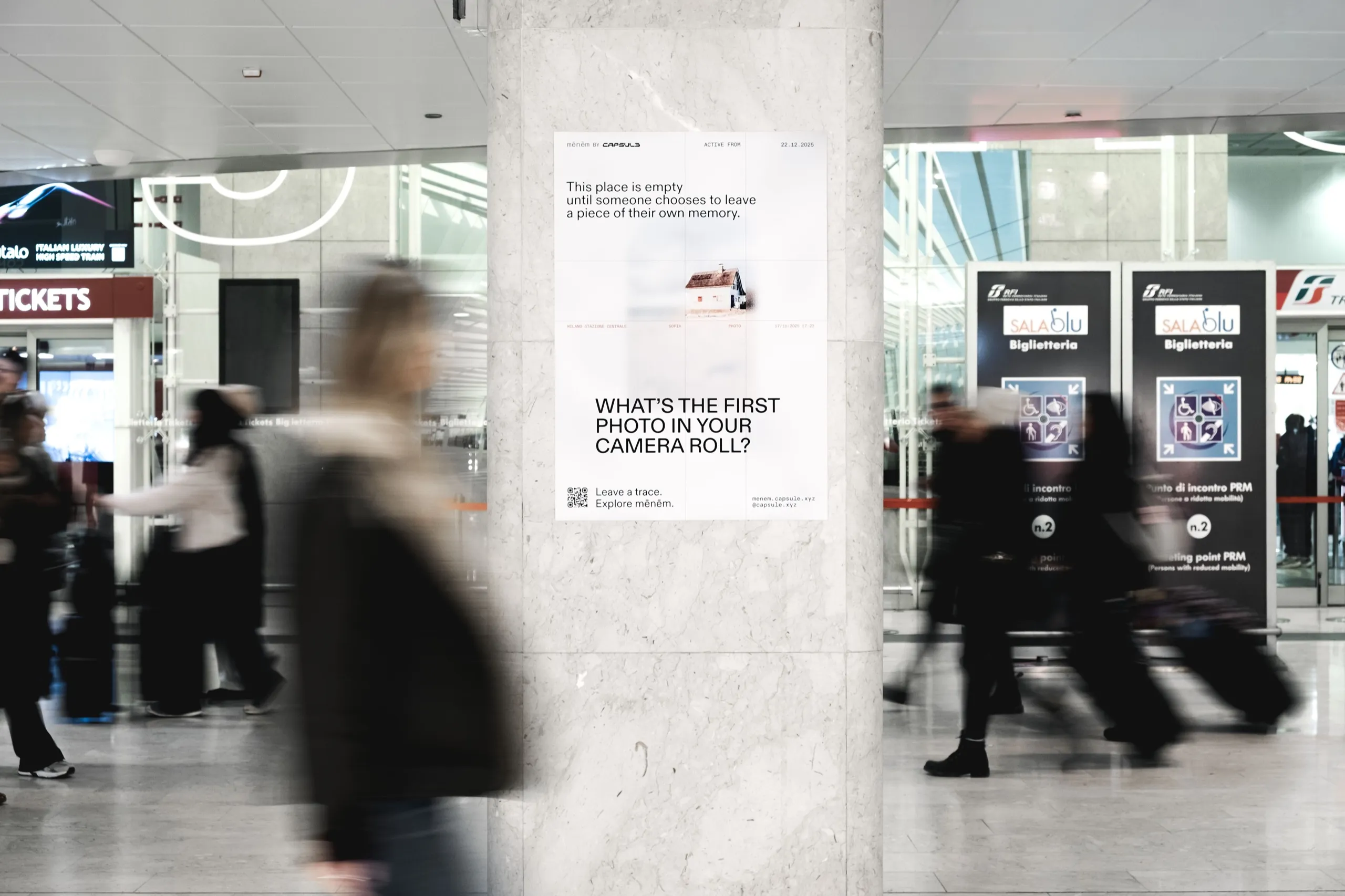 A Capsule poster in a station, asking What’s the first photo in your camera roll?, with passers-by in motion